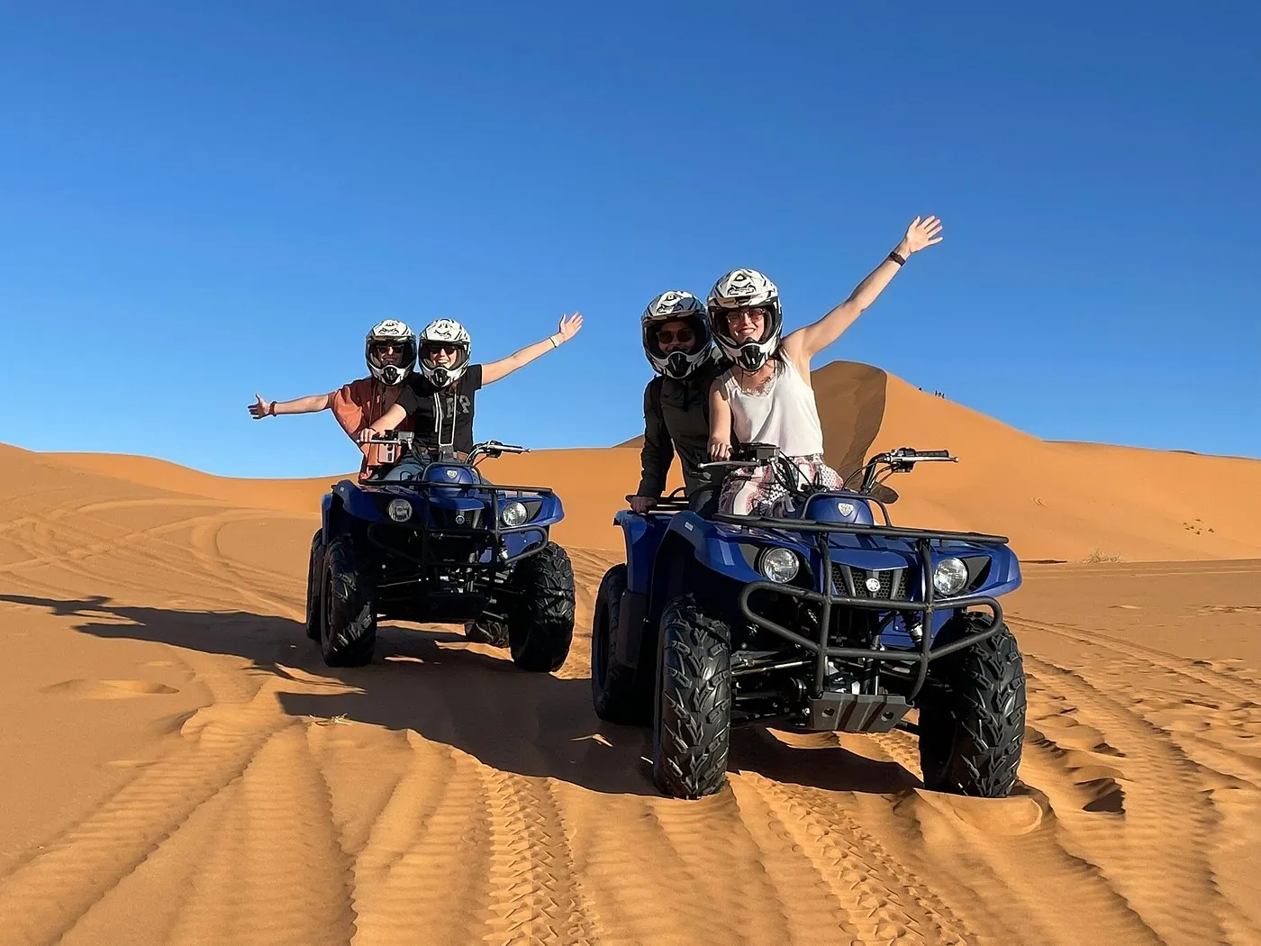 Quad bike rider crossing desert sand at sunset