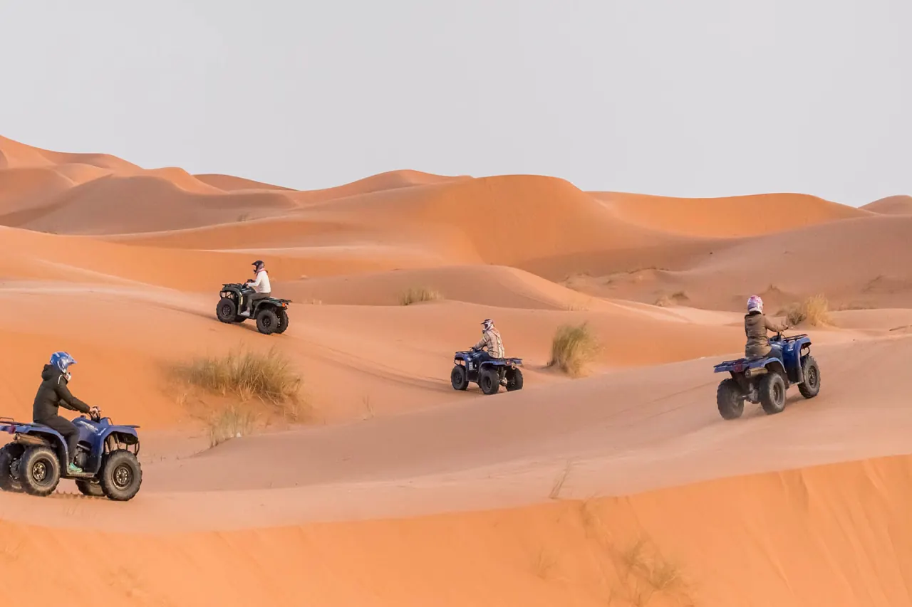 Quad-Fahrer bei der Abfahrt über eine goldene Düne